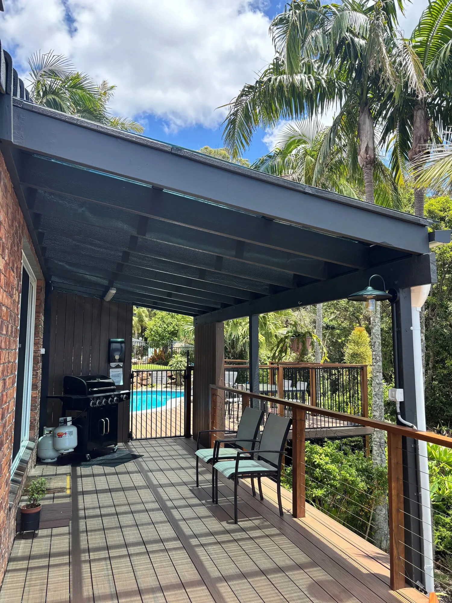 Covered deck with BBQ and seating beside the pool