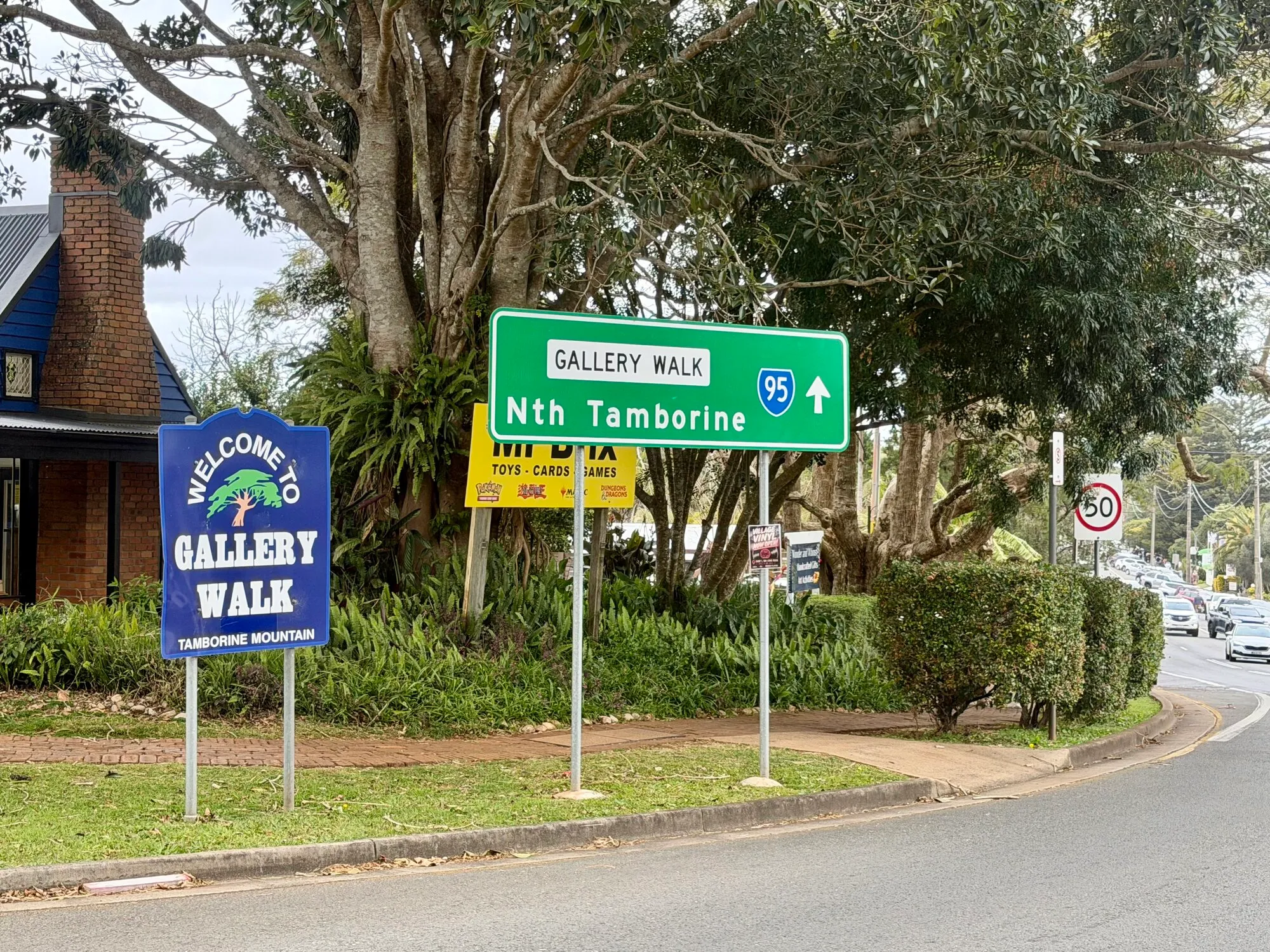 Welcome sign at the entrance to Gallery Walk, Tamborine Mountain's strip of shops, cafes and galleries, shaded by large fig trees